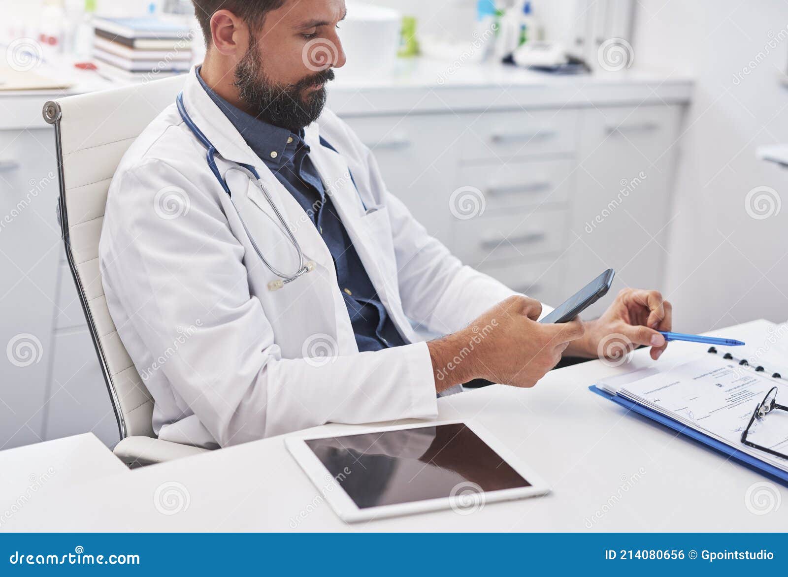 male doctor using mobile phone in his doctorÃ¢â¬â¢s office